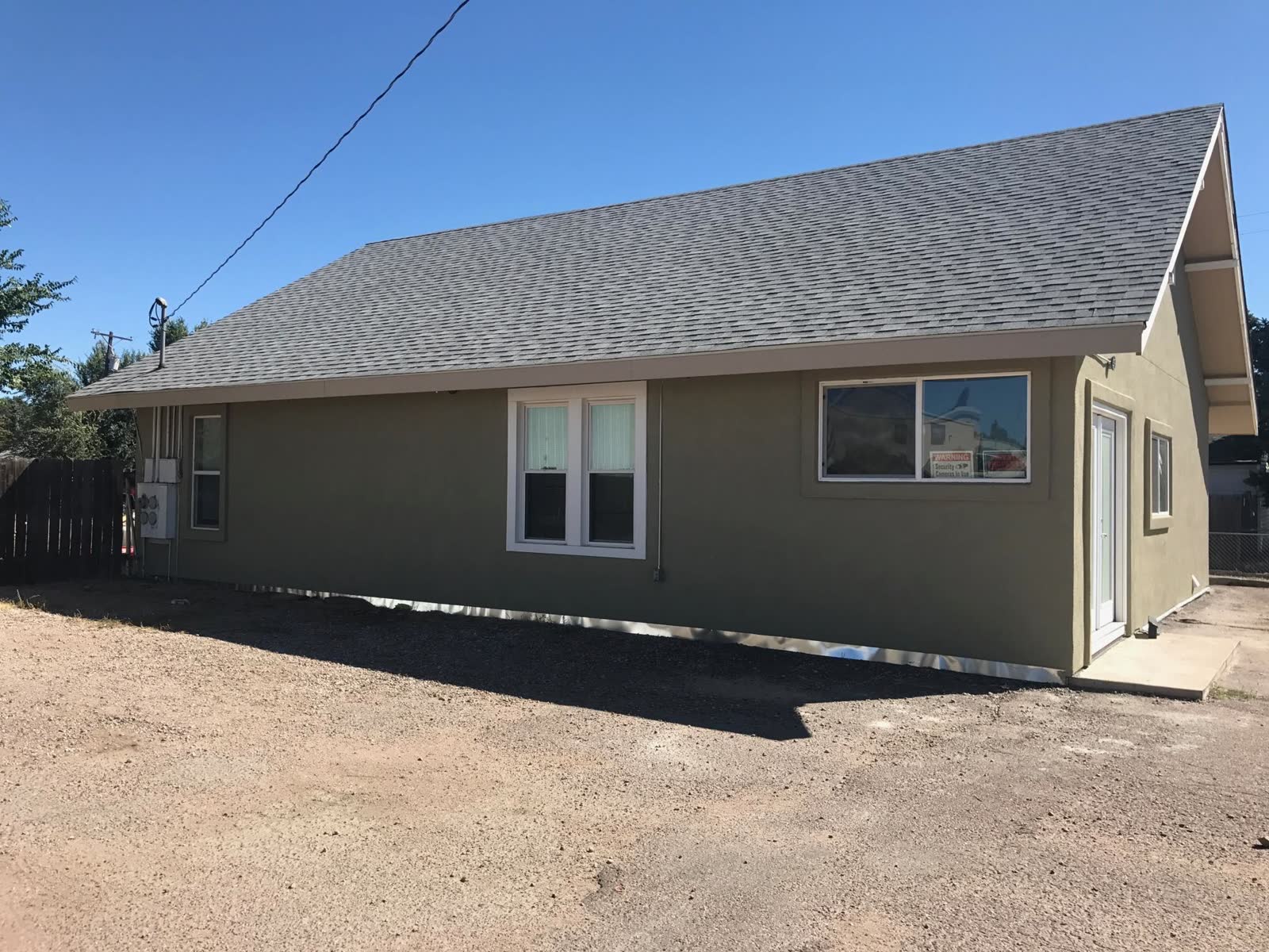 After: white wood-clad home converted to a sage-green stucco finish